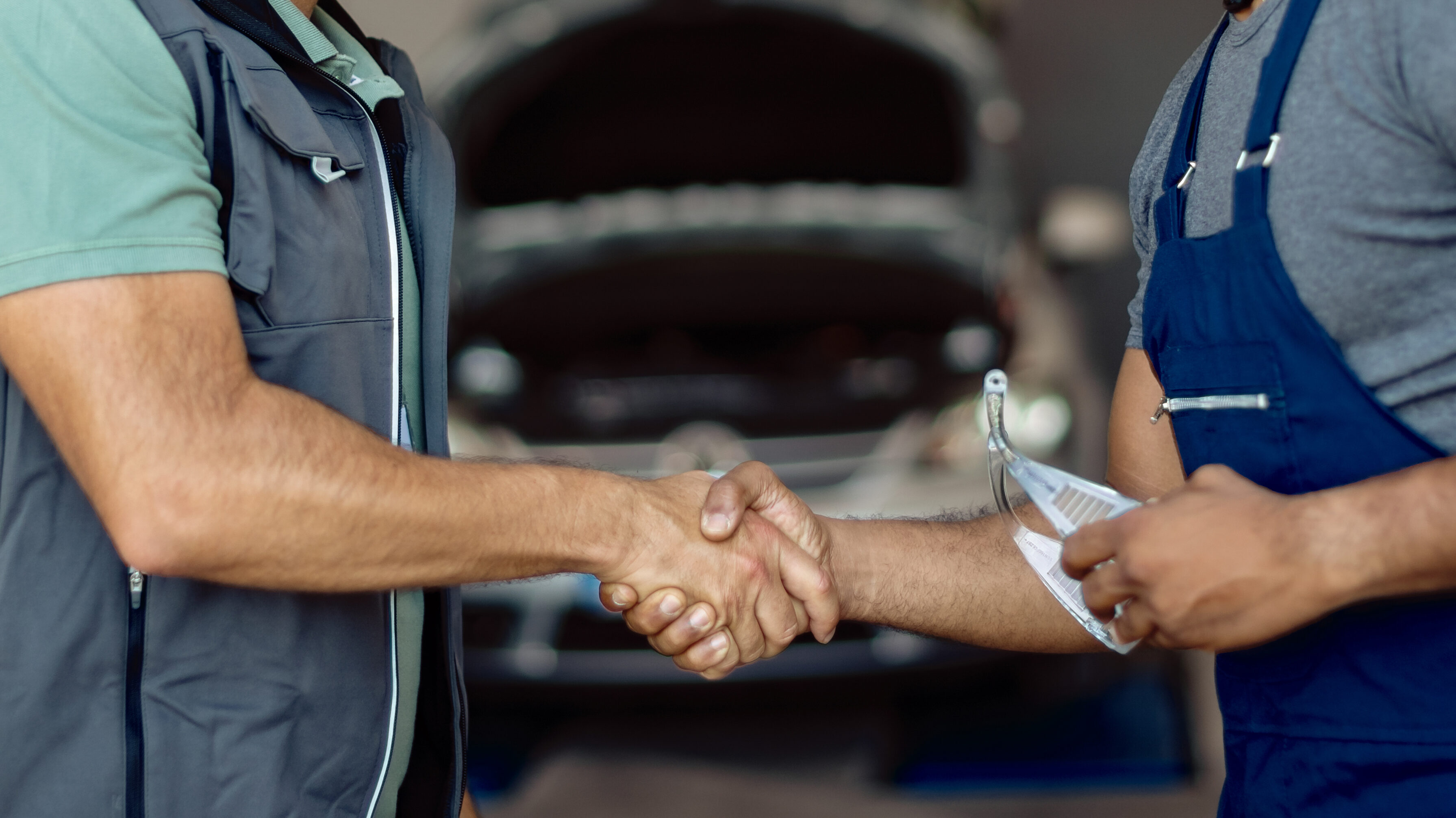 Cara Memilih Supplier Ban Alat Berat Untuk Armada Tambang Dan Konstruksi 2 Happy Mechanic Greeting With His African American Coworker Auto Repair Shop Edited