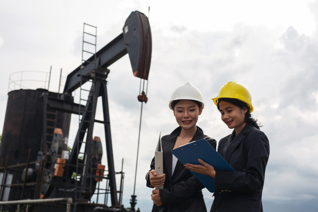 K3 Migas: Panduan Lengkap Untuk Mengelola Risiko Di Industri Migas 1 Two Female Engineers Stand Beside Working Oil Pumps With White Sky